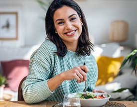 Woman smiling while eating healthy meal at home