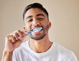 Man smiling while brushing his teeth