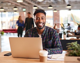 Man smiling while working on laptop in office