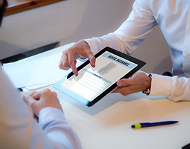 Someone holding digital pad showing “Dental Insurance” zooming in with two fingers